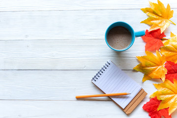 Wall Mural - Seasonal autumn maple leaves.  Cup coffee hot steaming  warm scarf with paper note for greeting text on wooden table background in morning relax sunny day. Lifestyle concept