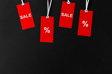 shopping, sale and outlet concept - red tags with discount signs on black background