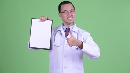 Sticker - Happy Asian man doctor showing clipboard and giving thumbs up