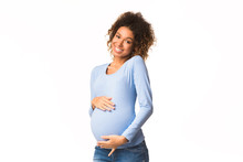 African-american Pregnant Woman Caressing Her Belly And Smiling