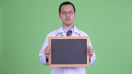 Canvas Print - Happy Asian man doctor talking while holding blackboard