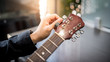 © zephyr_p - Male hand guitarist adjusting pegs on acoustic guitar during music lesson at home. String musical instrument concept