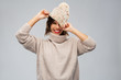 © Syda Productions - christmas, season and people concept - happy smiling young woman in knitted winter hat and sweater over grey background
