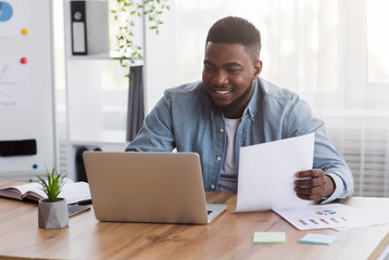 Aufkleber - Young black businessman working with laptop and papers in office