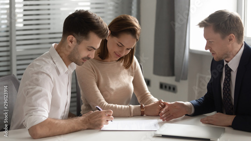 Fotografía Young couple making deal with manager, signing contract