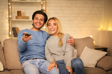 Wall Mural - Happy spouses watching TV on sofa in the evening