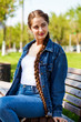 © Andrey_Arkusha - Beautiful girl in a denim jacket sits on a bench in a summer park