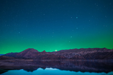 Wall Mural - beautiful lake and mountains in the starry night with green light over the mountains. night landscap