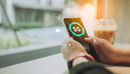 Poster - close up of hand holding a phone with a 5g hologram in coffee shop.wireless network systems.the conc