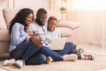 Father, mother and daughter using laptop at home together