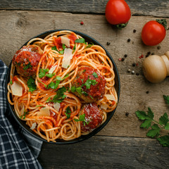 Wall Mural - Delicious spaghetti pasta with meatballs and tomato sauce in a bowl. Traditional American Italian food on a rustic wooden table. Top view shot.