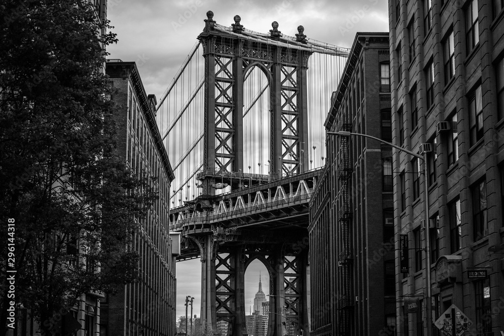 View of one of the towers of the Manhattan Bridge from the streets of the DUMBO district, Brooklyn, NYC black and white - obrazy, fototapety, plakaty 