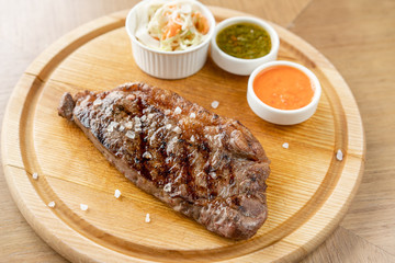 Grilled striploin steak with Pickled cabbage and two sauces. The strip steak, also called a New York strip. Serving on a wooden Board. Barbecue restaurant menu, a series of photos of different meats.