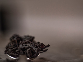 Dry black tea leaves on metal spoon