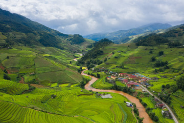 Aerial top view of paddy rice terraces, green agricultural fields in countryside or rural area of Mu Cang Chai, Yen Bai, mountain hills valley at sunset in Asia, Vietnam. Nature landscape background.