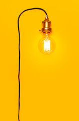 Vintage fashionable edison lamp on bright yellow background. Top view flat lay copy space. Creative idea concept, designer lamp, modern interior item. Lighting, electricity, background with lamp