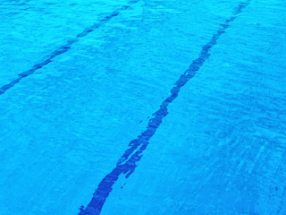 Pool with clear blue water. At the bottom of the pool, parallel lines are visible that cross the background diagonally