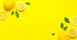 Creative background with fresh lemons and green leaves on bright yellow background. Top view flat lay copy space. Lemon fruit citrus minimal concept vitamin C. Composition with whole, slices of lemons