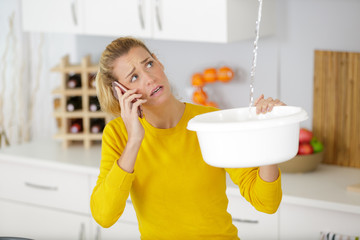 woman holding bucket while calling a plumber