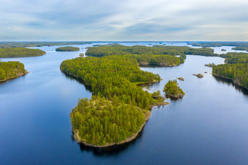 Canvas Print - Aerial view of of small islands on a blue lake Saimaa. Landscape with drone. Blue lakes, islands and green forests from above on a cloudy summer morning. Lake landscape in Finland.