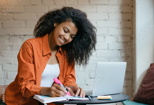 Fotomural Young attractive African American business woman working project, planning strategy, taking notes in modern office
