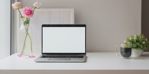 Open blank screen laptop computer with mock up frame with roses vase and coffee cup