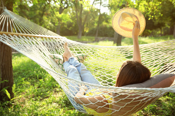 Poster - Young woman with hat resting in comfortable hammock at green garden