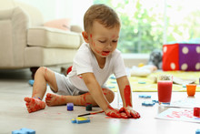 Cute Little Boy Playing With Paints On Floor In Living Room