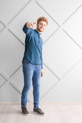 Wall Mural - Portrait of young man pointing at viewer near grey wall