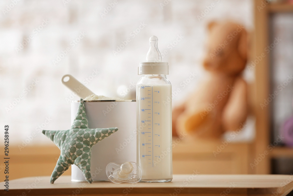 Bottle of milk and jar with baby formula on table in room - obrazy, fototapety, plakaty 