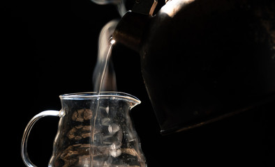 Wall Mural - The steam from a cup or pot of coffee or tea on the old wood table and black background, Warm drinks make good healthy, Selective focus.