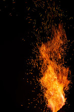 Flame Of Fire With Flying Burning Red Sparks On A Black Background. Fiery Orange Glowing Particles Flying Away In Night Sky. Closeup Of Beautiful Flame