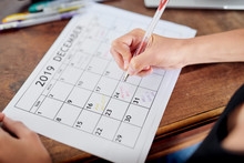 Girl Writing Reminders On Calendar Page For December 2019