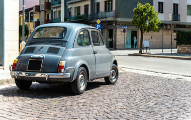 Wall Mural - Vintage small car on traditional italian paved street.