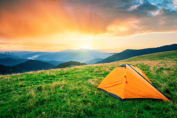 Wall Mural - orange tent in the mountains at sunset