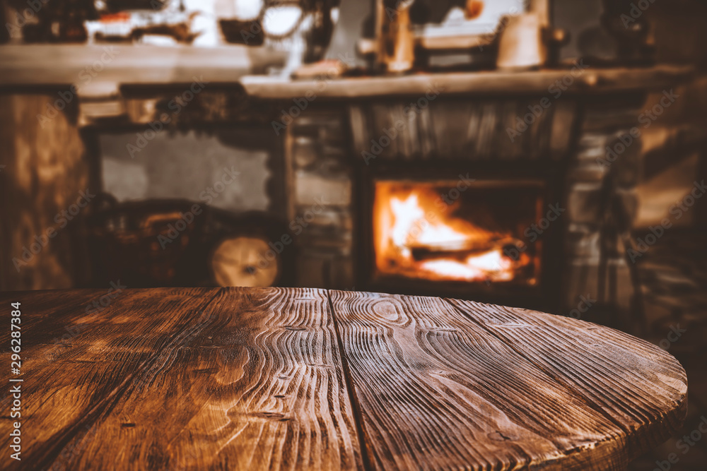 Table top with blurred fireplace and cosy home interior background. - obrazy, fototapety, plakaty 