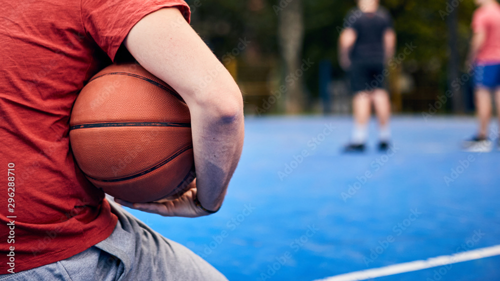 Man holding basketball ball on the urban city court. - obrazy, fototapety, plakaty 