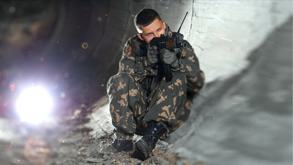 armed man in camouflage clothing in a tunnel with an assault rifle