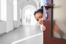Pretty African Girl Hiding From Opened Door In School.