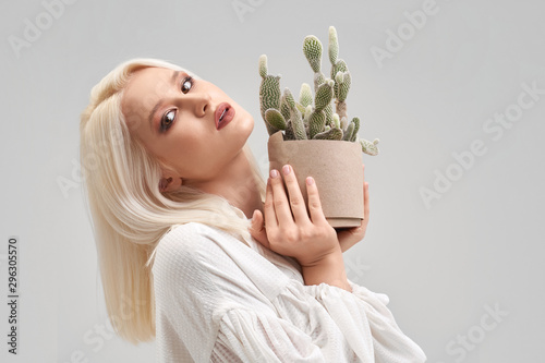 Fotografía Beautiful blonde girl with make up holding pot with cactus