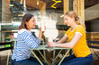 © mimagephotos - smiling mother and daughter sitting at cafe together having a drink