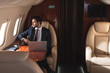© LIGHTFIELD STUDIOS - handsome businessman working with laptop in plane during business trip