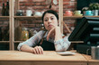 © PR Image Factory - Beautiful asian korean pensive barista in apron leaning on bar counter table in vintage coffee shop. startup business not successful concept. lady cafe owner bored waiting customer to come cafeteria