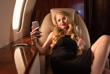 Attractive Passionate Girl Taking Selfie On Smartphone With Champagne In Airplane