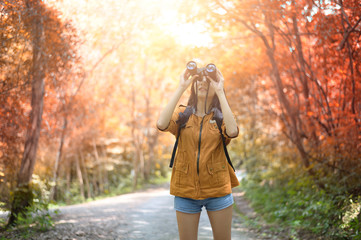 The girl is using binoculars to see the birds in the forest.