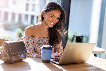 Beautiful Filipino woman using laptop at cafe