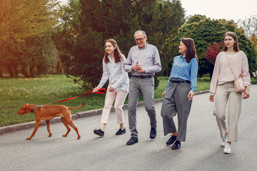 Family in a summer park. People walking with a dog. Parents with a two daughters