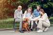 © hetmanstock2 - Family in a summer park. People sitting with a dog. Parents with a two daughters