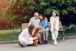 © hetmanstock2 - Family in a summer park. People sitting with a dog. Parents with a two daughters