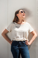 Wall Mural - happy middle aged woman laughing with sunglasses and looking up by white background